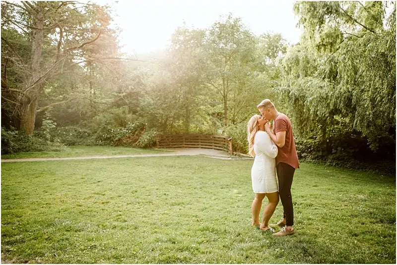 Snohomish & Seattle Wedding Photographer | GSquared Weddings Photography A couple stands close together on a grassy field in Washington Arboretum, holding hands and smiling at each other as sunlight filters through the trees in the background, capturing a perfect engagement moment. 47.9129° N, 122.0982° W | wedding photo by GSquared Weddings