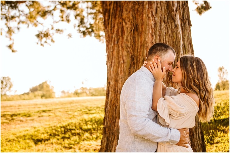 Snohomish & seattle wedding photographer | gsquared weddings photography a couple embraces lovingly under a large tree in a sunlit field at pemberton farm engagement snohomish gently touching foreheads and smiling as warm golden sunlight creates a romantic atmosphere | wedding photo by gsquared weddings
