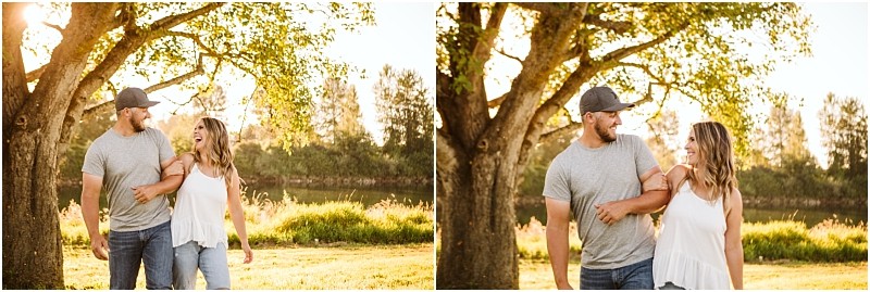 Snohomish & seattle wedding photographer | gsquared weddings photography a couple walks together in a sunlit park for their pemberton farm engagement smiling and looking at each other as they stroll under a tree near a river on a bright clear day | wedding photo by gsquared weddings