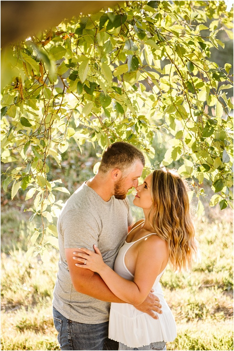 Snohomish & seattle wedding photographer | gsquared weddings photography a couple stands close together under a leafy tree branch at pemberton farm in snohomish gazing into each others eyes and embracing with sunlight filtering through the leaves in the background | wedding photo by gsquared weddings
