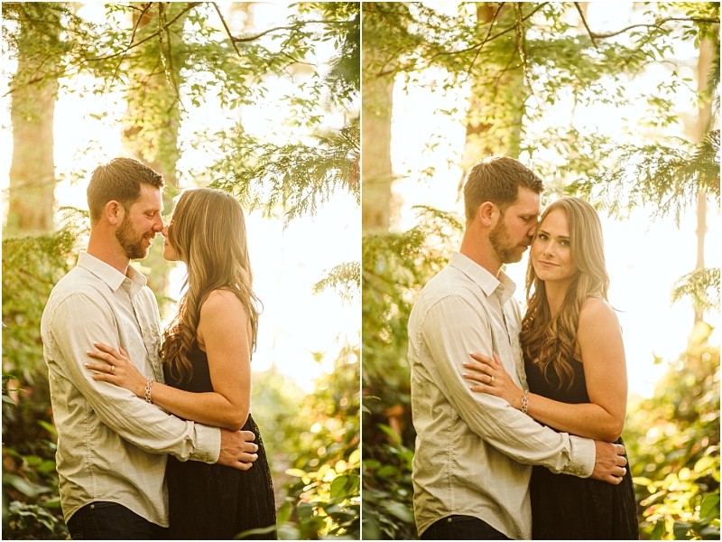 Snohomish & seattle wedding photographer | gsquared weddings photography a couple stands closely together outdoors among sunlit trees at deception pass embracing and looking affectionate during their august engagement The woman wears a black dress the man a light shirt his short hair and beard catching the golden light | wedding photo by gsquared weddings