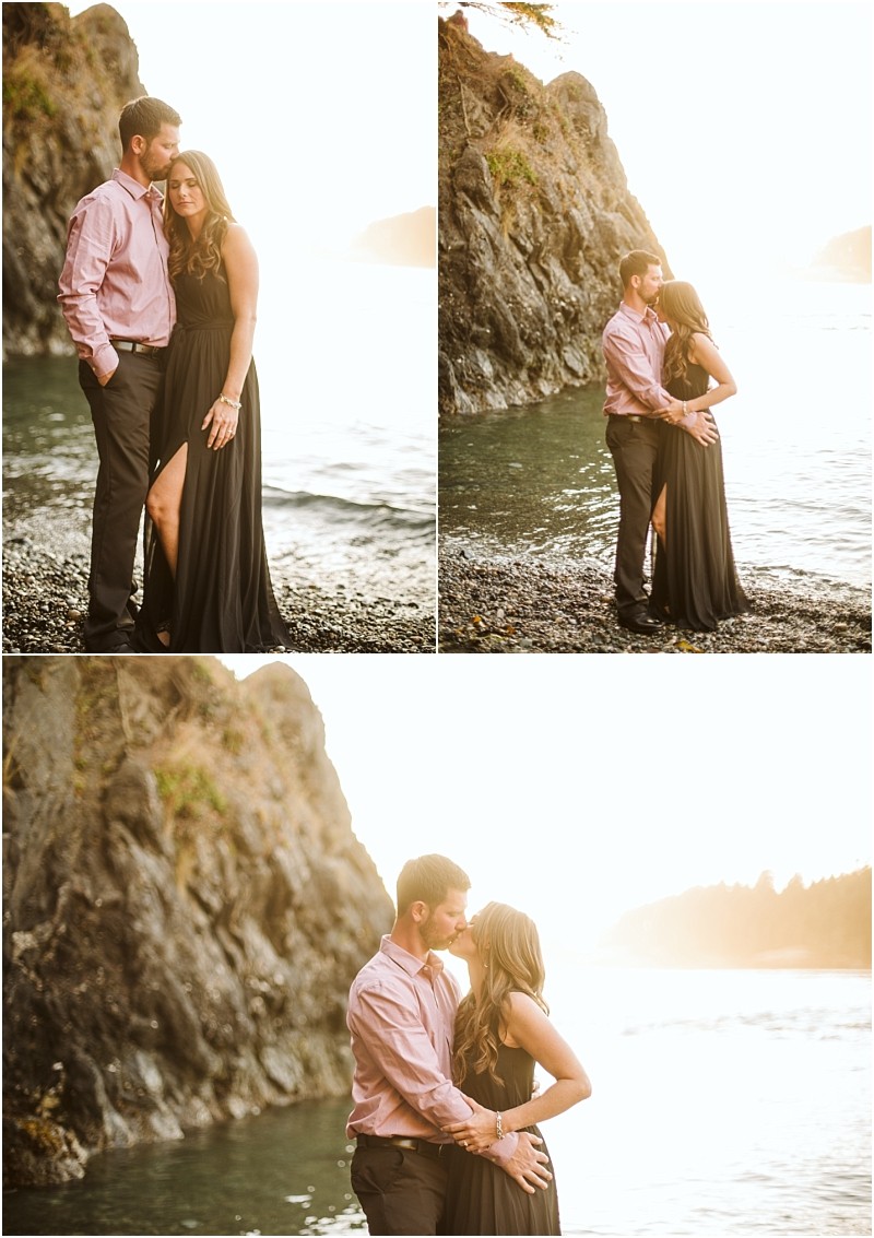 Snohomish & seattle wedding photographer | gsquared weddings photography a couple stands by the rocky deception pass shoreline at sunset The woman wears a long black dress with a slit and the man a light pink shirt and dark pants They embrace and look at each other lovingly during their august engagement | wedding photo by gsquared weddings