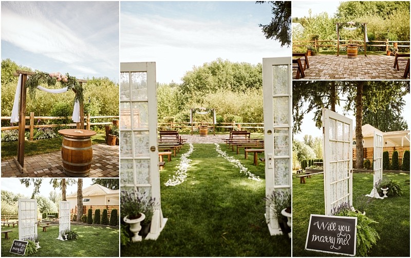 A rustic outdoor wedding setup in snohomish featuring wooden benches a wooden arch with greenery decorative barrels and vintage doors as an entrance A chalkboard sign reads will you marry me  the scene is surrounded by lush greenery Snohomish wedding photography