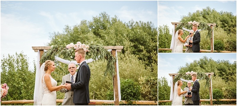 A bride and groom stand under a wooden arbor decorated with greenery and flowers exchanging vows outdoors with a smiling officiant The blue sky and snohomish trees create a picturesque backdrop for their special moment Snohomish wedding photography