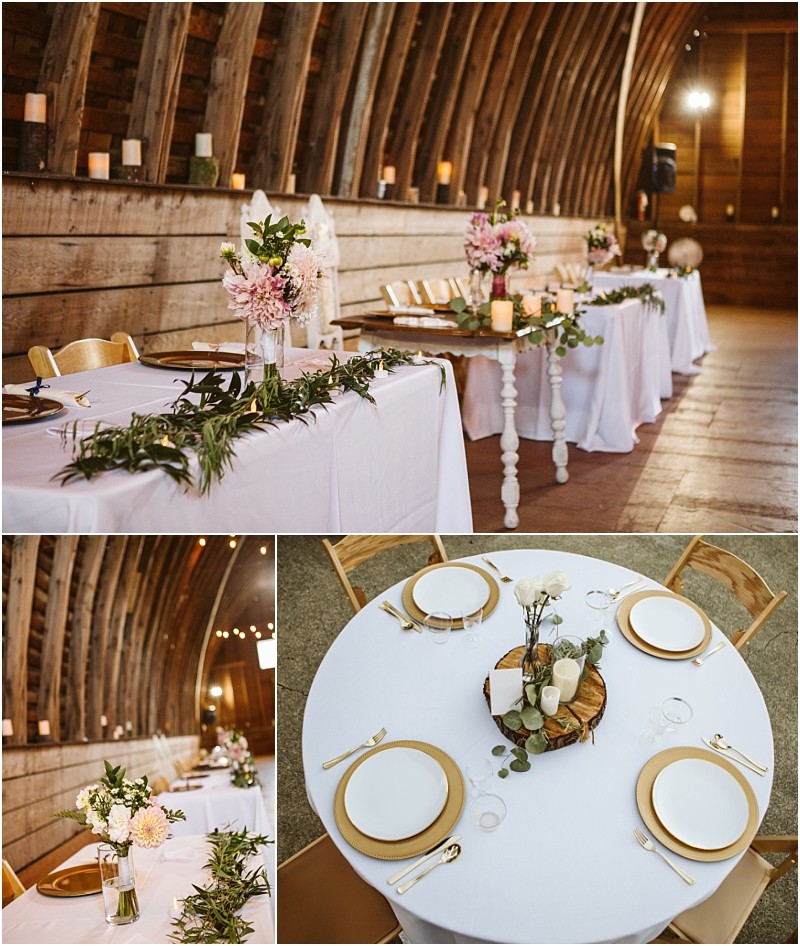 A rustic snohomish wedding reception setup inside a wooden barn with white clothed tables gold rimmed plates floral centerpieces candles and greenery garlands along the head table Snohomish wedding photography