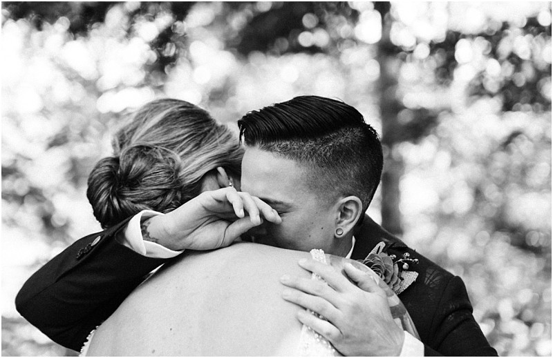 A black and white photo showing two people embracing closely in snohomish one wiping away tears while the other holds them gently The background is blurred highlighting the emotional moment between them Snohomish wedding photography