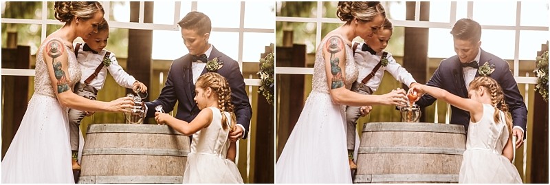 A bride groom and two children joyfully pour sand into a jar during an intimate wedding unity ceremony in snohomish standing together around a wooden barrel Snohomish wedding photography