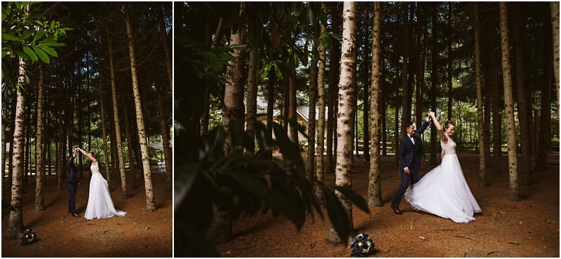 A bride and groom dance together in a snohomish forest surrounded by tall trees and dappled sunlight The bride wears a white dress and the groom is in a dark suit A bouquet rests on the mossy forest floor nearby Snohomish wedding photography