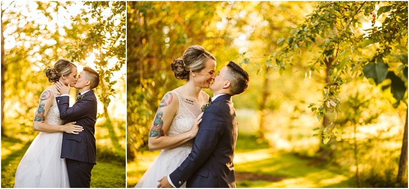 Two brides in wedding attire stand close together outdoors in snohomish embracing and smiling at each other under sunlit trees captured in warm golden light Snohomish wedding photography