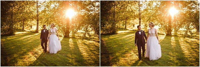 A couple dressed in wedding attire walks hand in hand through a sunlit grassy snohomish park surrounded by trees with golden sunlight streaming through the branches Snohomish wedding photography