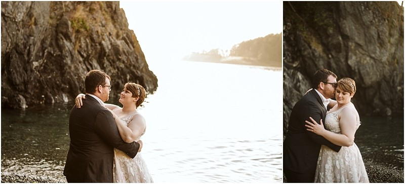 A couple dressed in wedding attire embraces by the waters edge in snohomish with rocky cliffs in the background bathed in soft golden sunlight Snohomish wedding photography