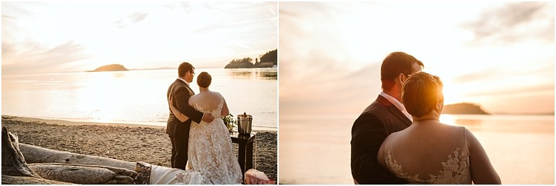 A bride and groom stand close together on a sandy snohomish beach at sunset looking out over calm water with soft golden light and distant islands in the background Snohomish wedding photography