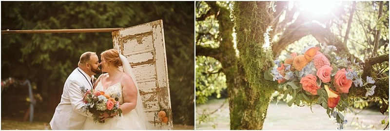A bride and groom smile and embrace outdoors near an old wooden door in snohomish holding a colorful bouquet next to them the bouquet rests on a mossy tree branch in sunlight Snohomish wedding photography