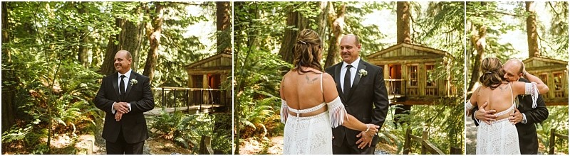 A groom in a suit sees his bride in a white dress for the first time in a snohomish forest setting they smile and embrace in front of a wooden cabin surrounded by trees Snohomish wedding photography