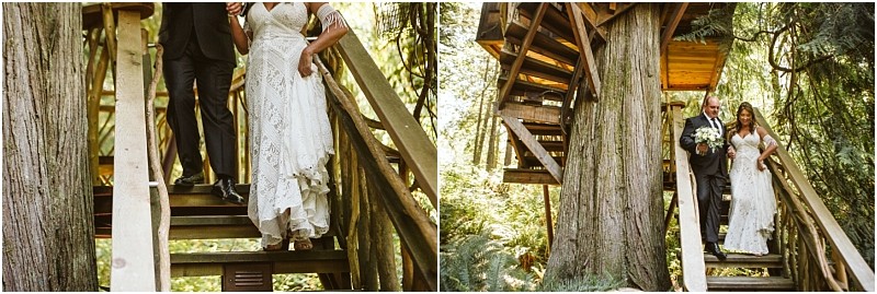 A bride in a white lace dress descends wooden stairs outside among tall snohomish trees accompanied by an older man in a suit Sunlight filters through the forest creating a warm rustic atmosphere Snohomish wedding photography
