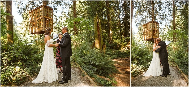 A bride and groom exchange vows and share a kiss in a lush snohomish forest with a small wooden treehouse above them Ferns and tall trees create a natural romantic backdrop Snohomish wedding photography