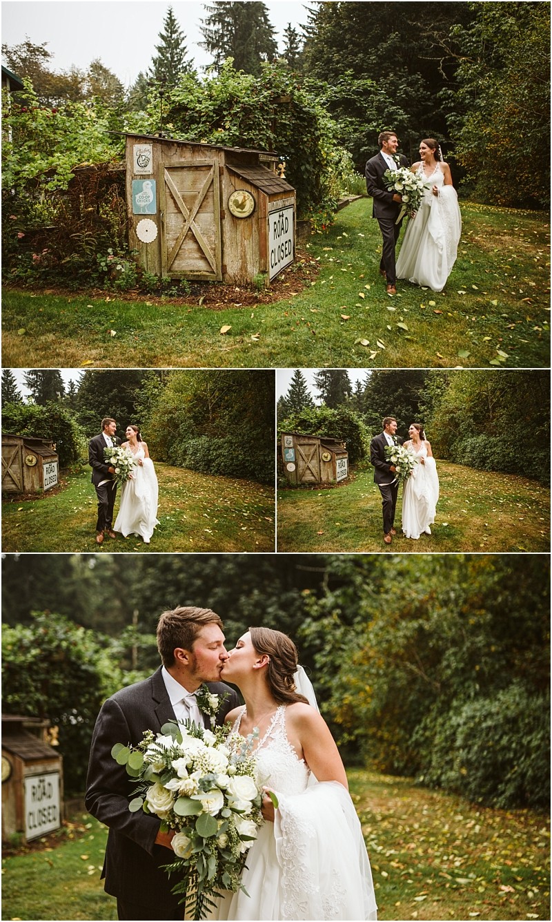 A bride and groom walk and kiss in a lush green outdoor snohomish setting near a rustic shed with vintage road signs The bride wears a white dress and carries a bouquet the groom wears a dark suit Snohomish wedding photography
