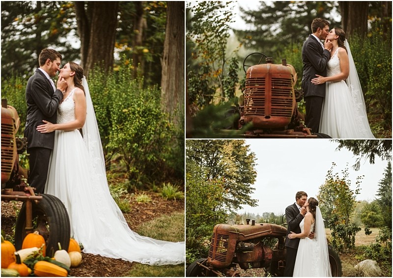 A bride and groom in wedding attire embrace and kiss near an old rusty tractor in a snohomish wooded outdoor setting surrounded by greenery and autumn pumpkins Snohomish wedding photography