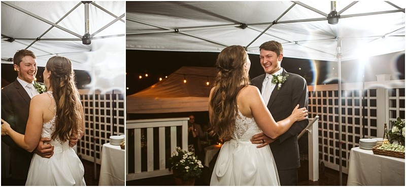 A bride and groom share a joyful first dance under a white tent at night in snohomish smiling at each other The area is decorated with white lattice panels string lights and a table with food nearby Snohomish wedding photography