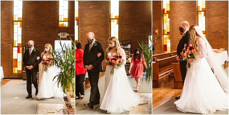 A bride in a white gown and face mask walks down the aisle arm in arm with an older man in a suit both masked inside a snohomish church with stained glass windows Other masked guests are visible in the background Snohomish wedding photography