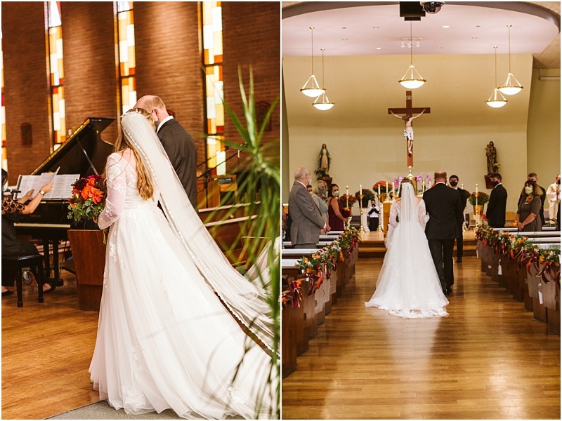 A bride in a white gown with a long veil walks down the aisle of a decorated snohomish church accompanied by a man in a suit as guests look on and a cross stands at the altar Snohomish wedding photography