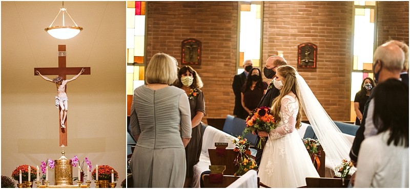 A bride in a white gown and veil wearing a mask stands with guests in a flower adorned snohomish church To the left a crucifix hangs above the altar surrounded by candles and elegant floral arrangements Snohomish wedding photography