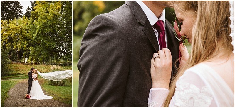 A bride and groom embrace outdoors on a snohomish path lined with greenery in a close up the bride touches the grooms suit and veil while holding a flower highlighting her ring and the grooms dark suit with a red tie Snohomish wedding photography