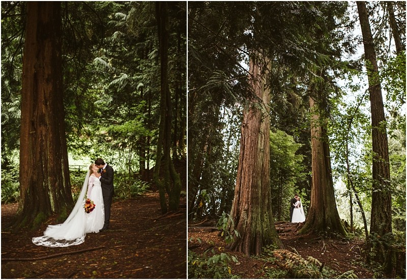 A bride and groom stand together in a snohomish forest surrounded by tall trees and greenery The bride wears a long white dress and holds a bouquet while the groom is dressed in a dark suit Snohomish wedding photography