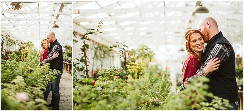 A couple embraces and smiles among lush green plants inside a bright snohomish greenhouse with white ceilings and large windows The woman has red hair and wears a maroon top the man is bald with a beard and wears a black vest Snohomish wedding photography