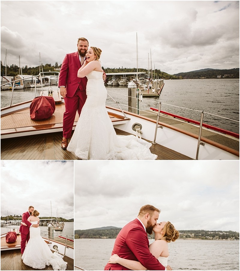 A bride in a white gown and a groom in a burgundy suit celebrate on a boat by a snohomish dock embracing and kissing with a scenic lake and forested hills in the background Snohomish wedding photography
