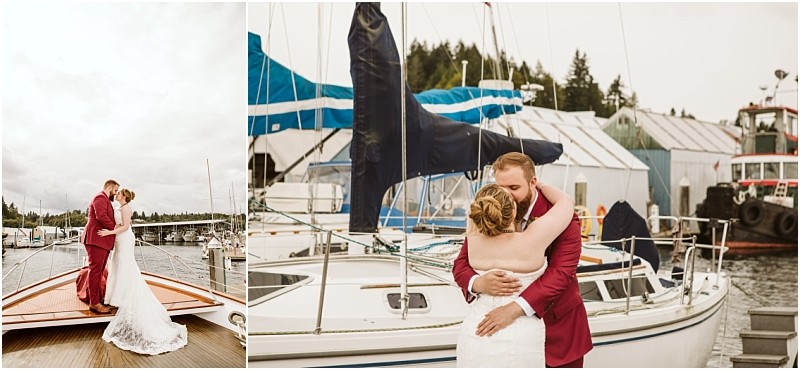 A bride and groom embrace on a snohomish marina dock beside sailboats The groom wears a maroon suit and the bride wears a white strapless dress Trees and boathouses are visible in the background Snohomish wedding photography