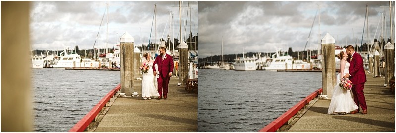 A bride and groom walk hand in hand along a dock in snohomish smiling at each other as boats and yachts rest in the background beneath a cloudy sky Snohomish wedding photography