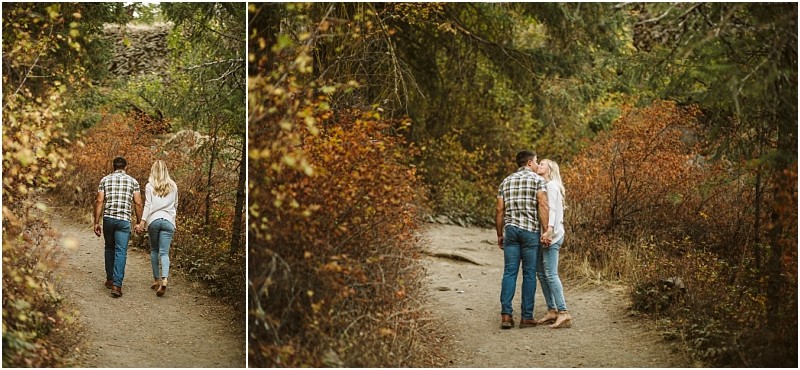 A couple walks hand in hand down a dirt path surrounded by autumn trees in snohomish then stops to share a kiss in the middle of the trail Snohomish wedding photography