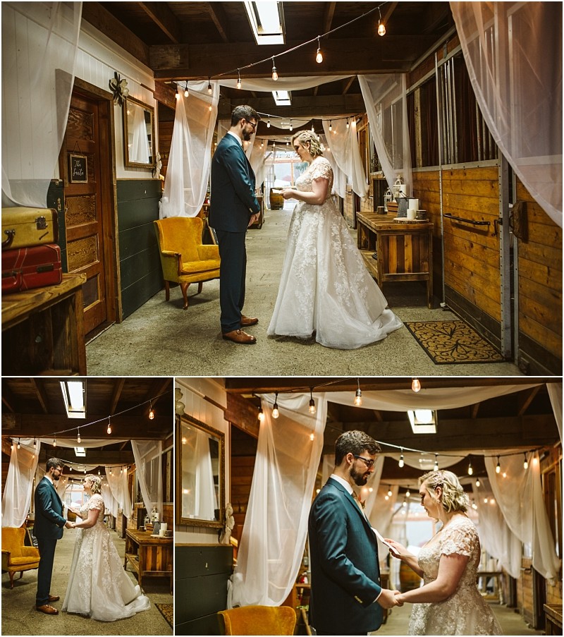 A bride and groom stand facing each other in a rustic snohomish hallway draped with white curtains and string lights The bride wears a white gown the groom a blue suit They hold hands and share an emotional moment together Snohomish wedding photography
