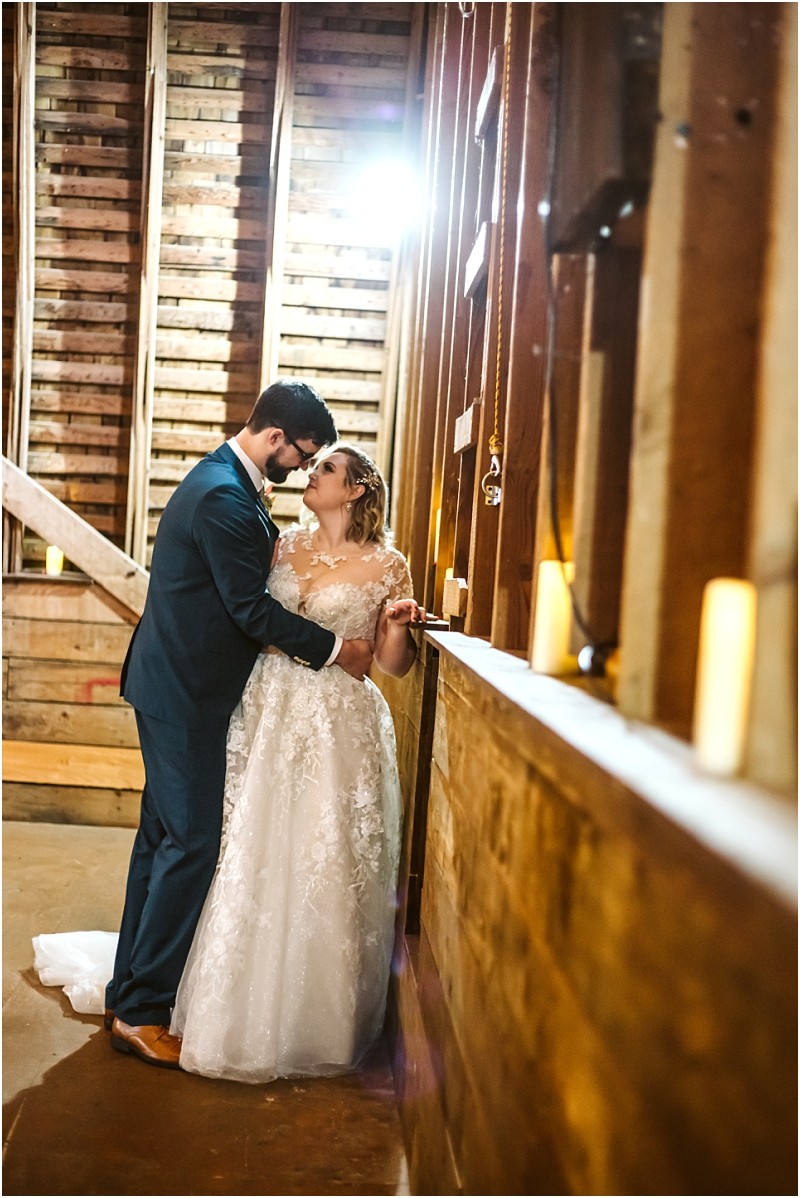 A bride and groom embrace and gaze at each other lovingly inside a rustic snohomish wooden barn illuminated by soft candlelight and sunlight streaming through the wooden beams Snohomish wedding photography