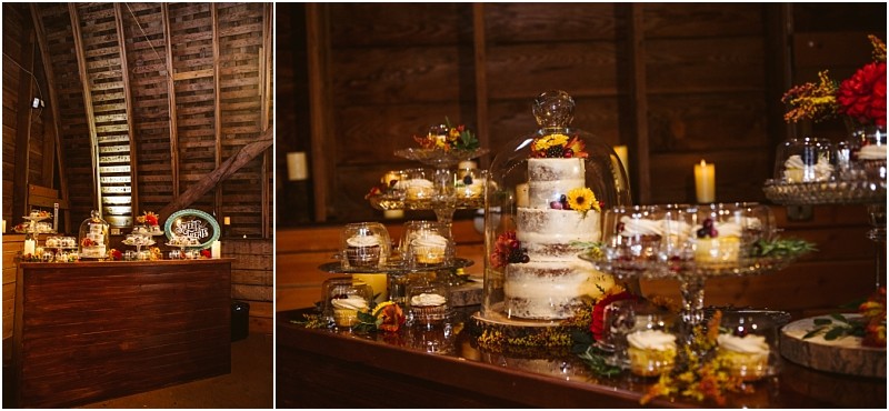 A rustic dessert table in snohomish features a semi naked tiered cake decorated with flowers assorted mini desserts in jars candles and autumnal floral accents all set against wooden walls inside a barn Snohomish wedding photography