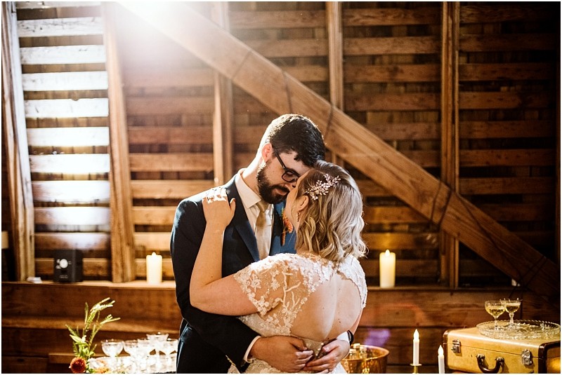 A bride and groom share a romantic dance in a rustic wooden snohomish venue with soft candlelight champagne glasses and warm sunlight streaming in from above Snohomish wedding photography