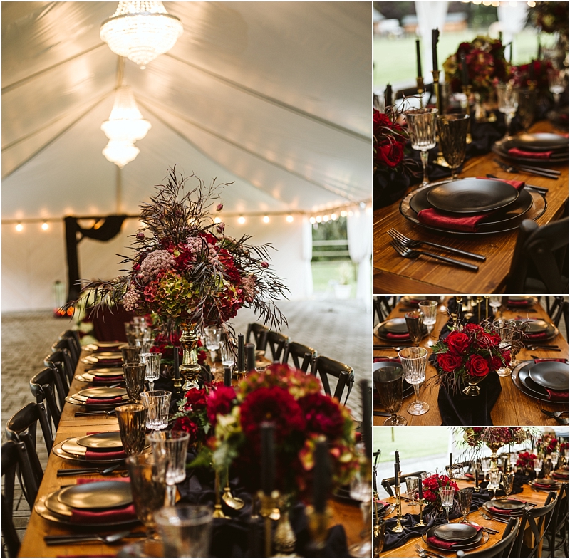 A long wooden table set for an event under a white tent in snohomish decorated with dark plates red napkins elegant glassware and lush floral centerpieces featuring red and purple flowers and greenery Snohomish wedding photography