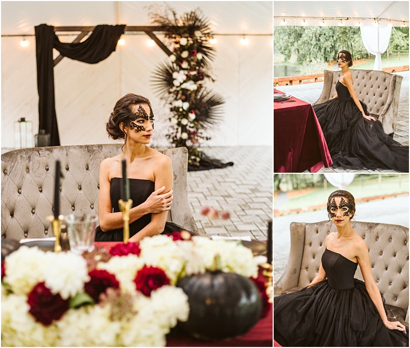 A woman in a strapless black gown and black lace mask sits on a tufted chair at an elegant table decorated with white and burgundy flowers set against dramatic snohomish inspired black and floral décor in the background Snohomish wedding photography