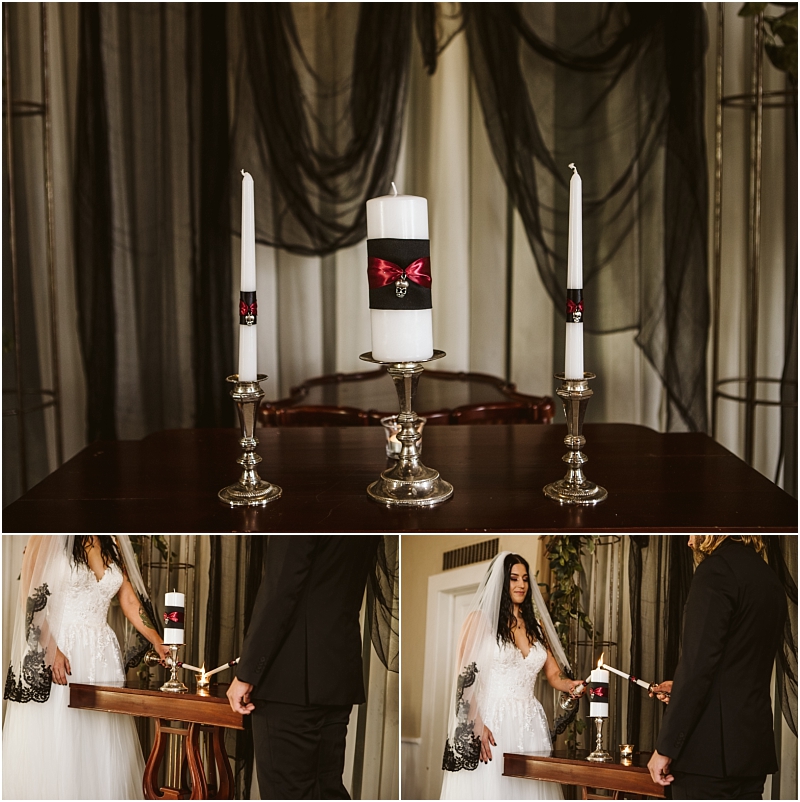 A snohomish wedding unity candle display with two white tapers and a large center candle wrapped in black and red ribbon rests on a dark table below a bride and groom light the unity candle together Snohomish wedding photography