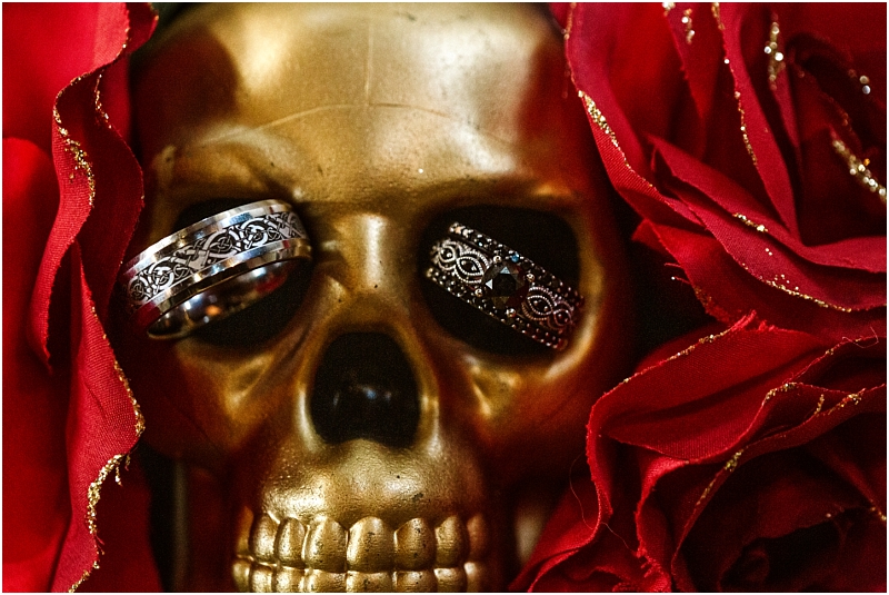 A gold skull surrounded by red roses with two ornate rings placed on its eye sockets inspired by the artistic spirit of snohomish Snohomish wedding photography
