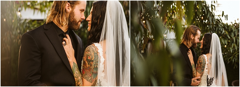 A bride with a tattooed arm and a veil lovingly gazes at her groom who wears a black suit as they stand close together outdoors among lush green foliage in scenic snohomish Snohomish wedding photography