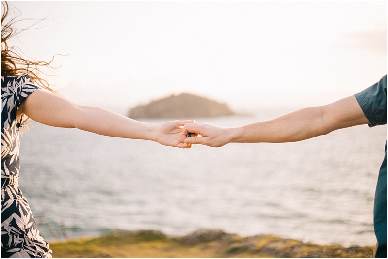 Two people are holding hands with outstretched arms standing by the water near snohomish with an island blurred in the background Only their arms and part of their torsos are visible The lighting is soft and natural Snohomish wedding photography Two people are holding hands with outstretched arms standing by the water near snohomish with an island blurred in the background Only their arms and part of their torsos are visible The lighting is soft and natural Snohomish wedding photography