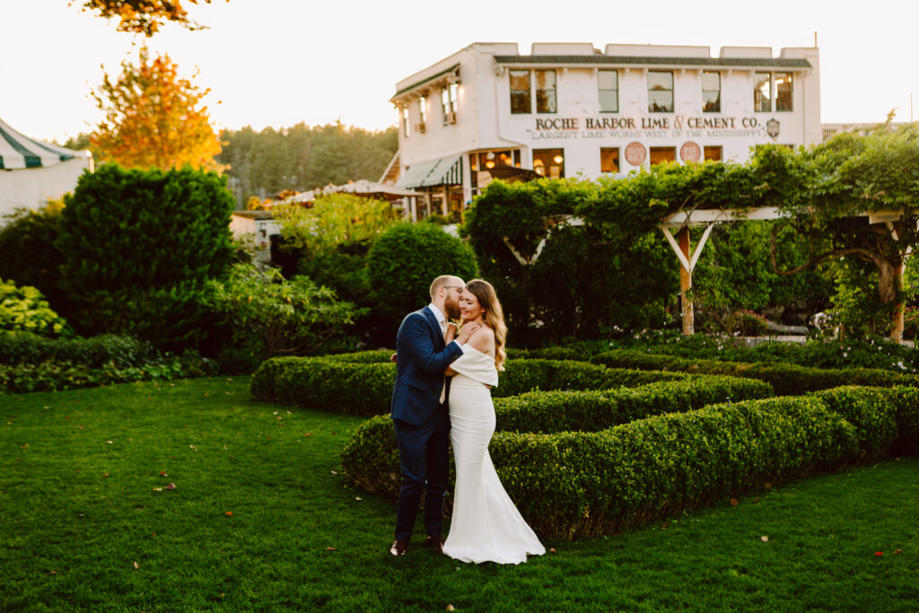 A bride and groom embrace and smile in a manicured garden at sunset with a historic white building labeled Roche Harbor Lime Cement Co in the backgroundone of the most charming Seattle wedding venues surrounded by lush greenery Snohomish Wedding Photography A bride and groom embrace and smile in a manicured garden at sunset, with a historic white building labeled “Roche Harbor Lime & Cement Co.” in the background—one of the most charming Seattle wedding venues surrounded by lush greenery. Snohomish Wedding Photography