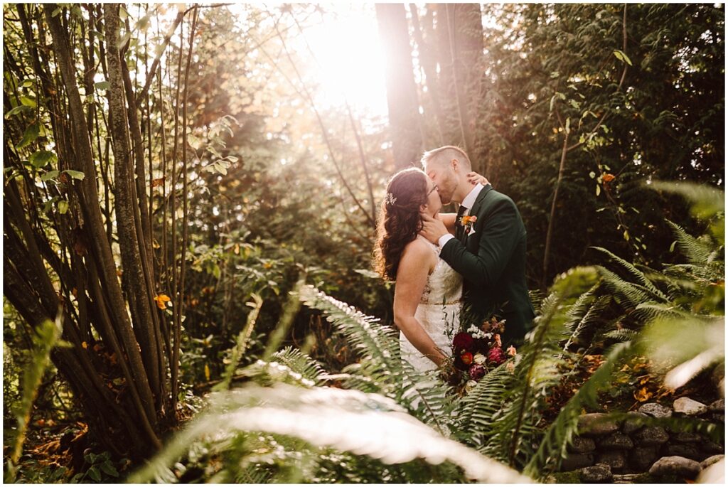 Lodge at st edward grotto bride and groom kissing in the sunlight behind the ferns Grotto at lodge at st edward wedding