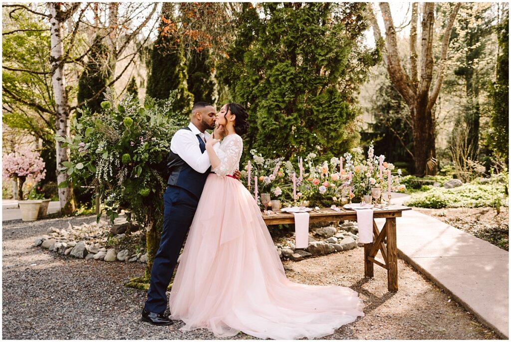Jardin del sol snohomish wedding venue styled shoot aurora with pollen in love bride in pink and white wedding gown and groom in blue suit by a garden and table