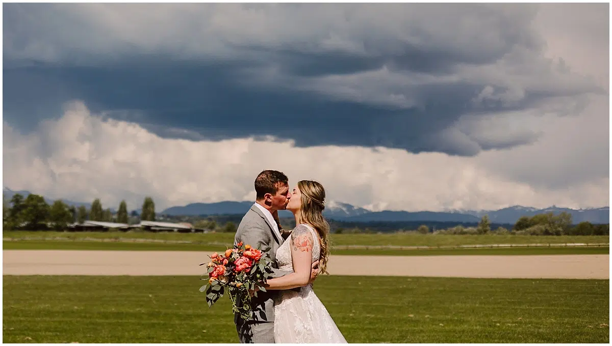 spring hidden meadows wedding bride and groom with stormy skies in the snohomish valley in for the luv of bridal dress with flowers by flora d'amore