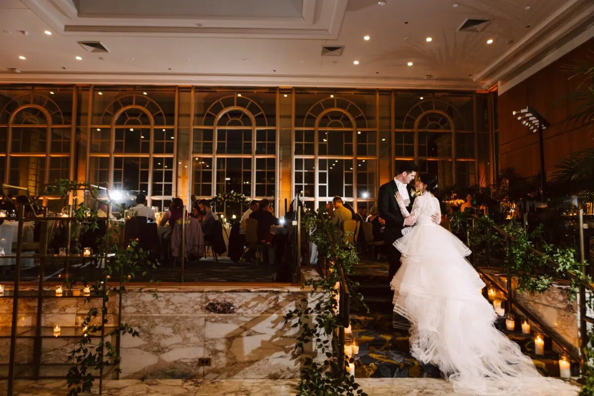 fairmont olympic winter wedding bride and groom standing on the stairs in the garden room with their guests behind them.
