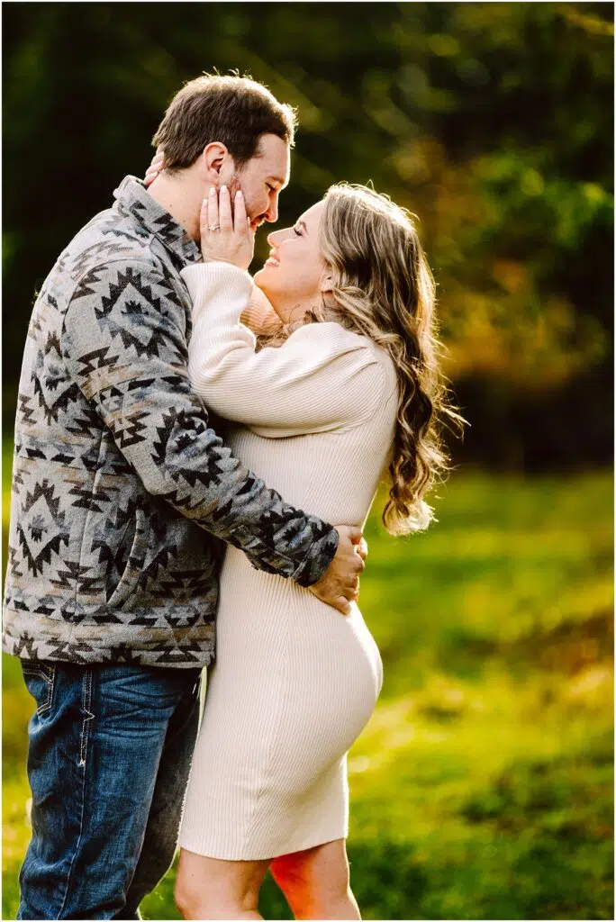Snohomish Wedding Photographer GSquared Weddings A couple embracing closely outdoors celebrating their engagement The woman in a cream dress gently touches the mans face who is wearing a patterned jacket and jeans They are surrounded by vibrant green foliage and warm sunlight capturing their joyous moment Serving Seattle Snohomish and Washington State