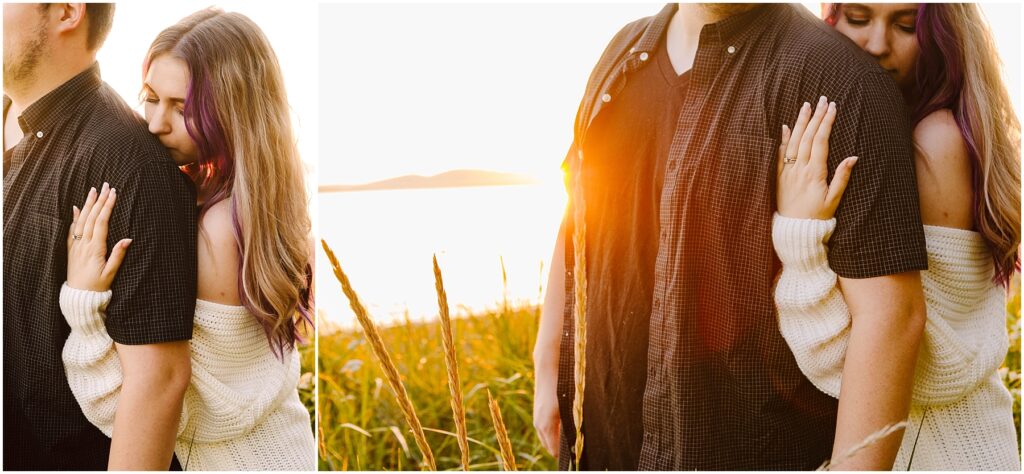 Snohomish Wedding Photographer GSquared Weddings A couple stands in a sunlit field by a lake during sunset. The woman, wearing a white sweater, embraces the man from behind, resting her head on his shoulder. Tall grass sways around them, and the sun casts a warm glow over the scene. Serving Seattle, Snohomish and Washington State